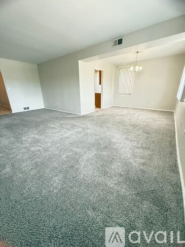A room with a grey carpet and a logo that says "avail" on the bottom right.