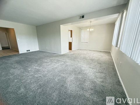 A spacious room with a grey carpet and white walls.