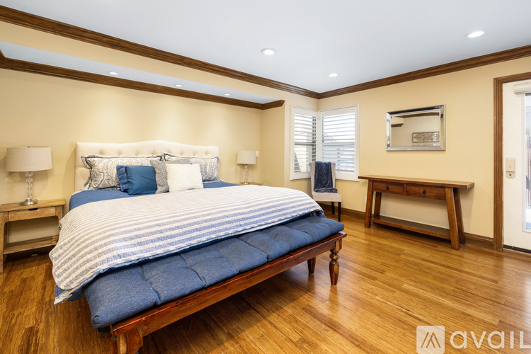 A bedroom with a large bed and wooden floors.