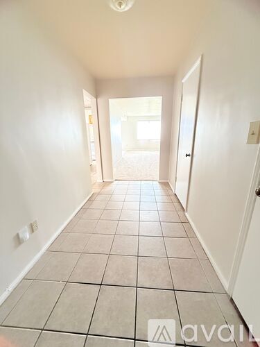 A long hallway with tiled floors and white walls.