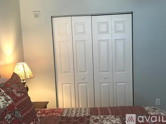 A bedroom with a bed, a lamp, and a white door.