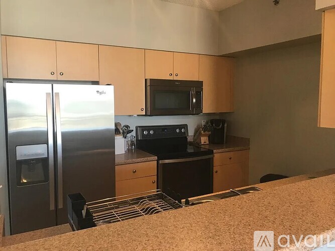 A kitchen with a refrigerator, microwave, oven, and sink.