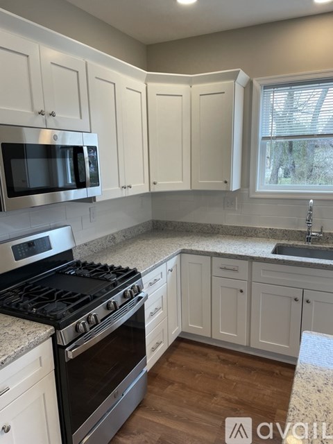 A kitchen with white cabinets and a black stove top oven.