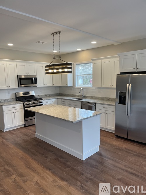 A kitchen with a large island in the middle and stainless steel appliances.
