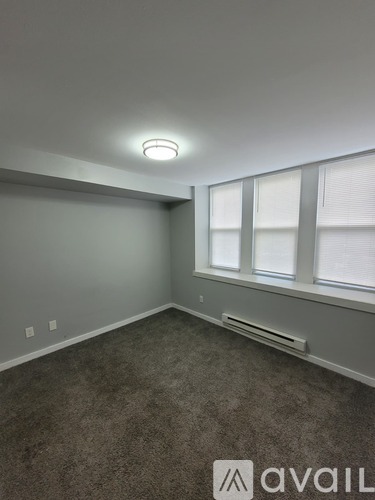 A room with a carpeted floor and a window with blinds.