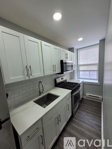 A kitchen with white cabinets and a grey floor.