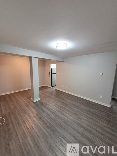 A room with a wooden floor and a white column in the middle.