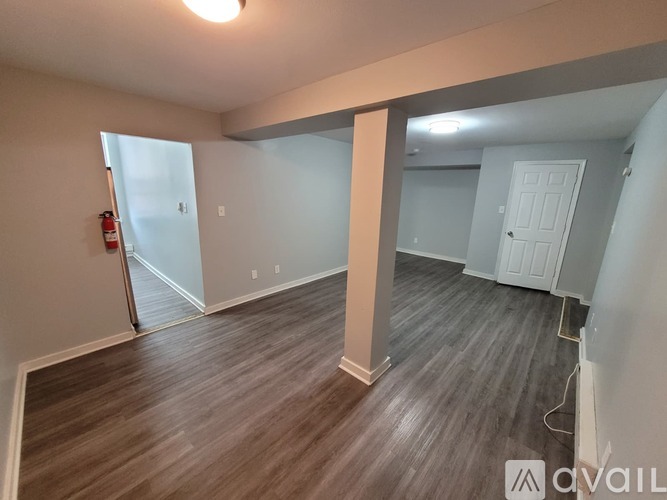 A room with wooden flooring and a fire extinguisher on the left side.