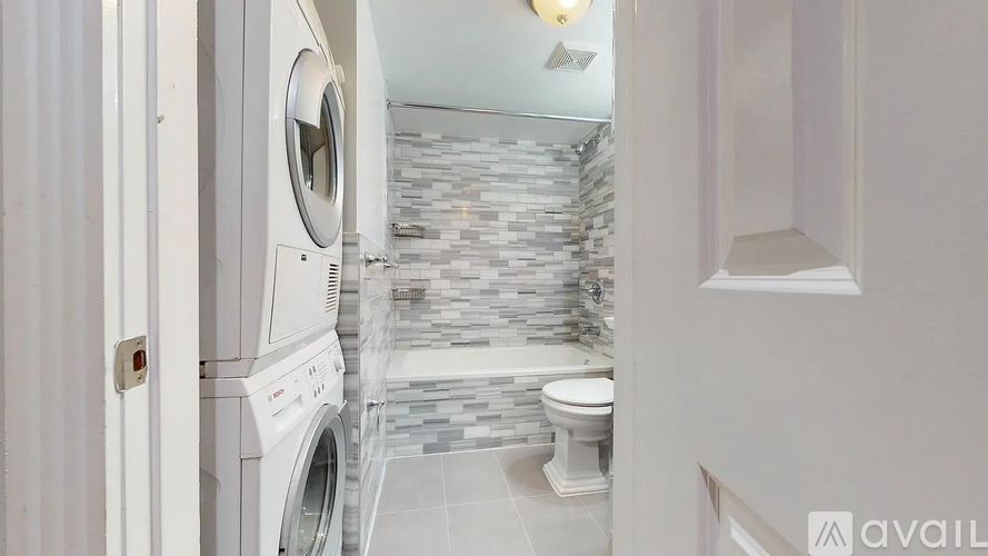 A washing machine is installed in a small bathroom.