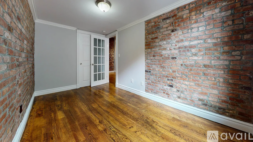 A room with a brick wall and wooden flooring is available for rent.