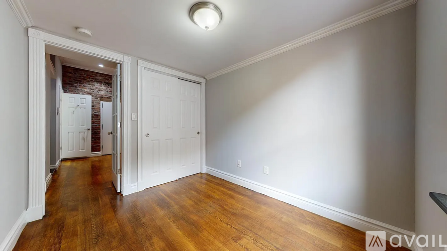 A room with wooden floors and white walls, with a doorway leading to another room.