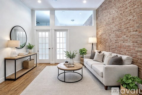 A living room with a white couch, a round table, and a brick wall.