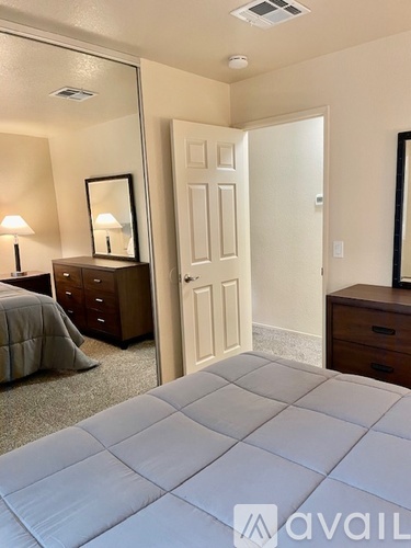 A bedroom with a large bed, a dresser with a mirror, and a nightstand with a lamp.