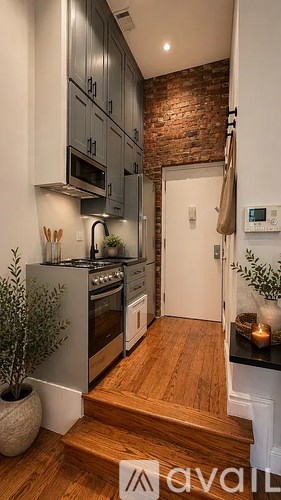 A kitchen with a brick wall and wooden floors.