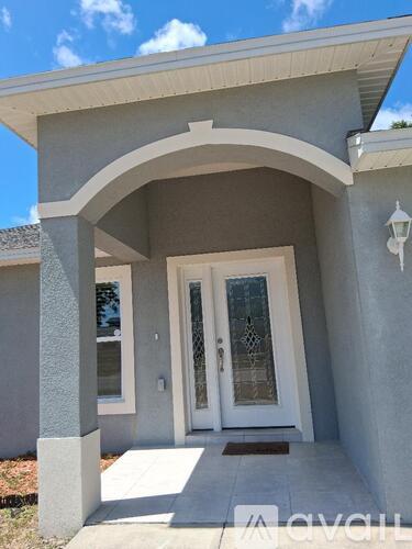 A house entrance with a white door and a grey wall.