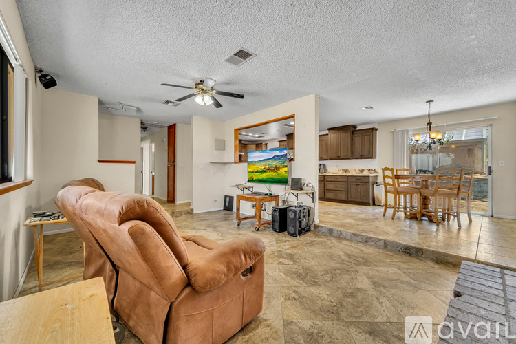 A living room with a brown leather couch and a ceiling fan.