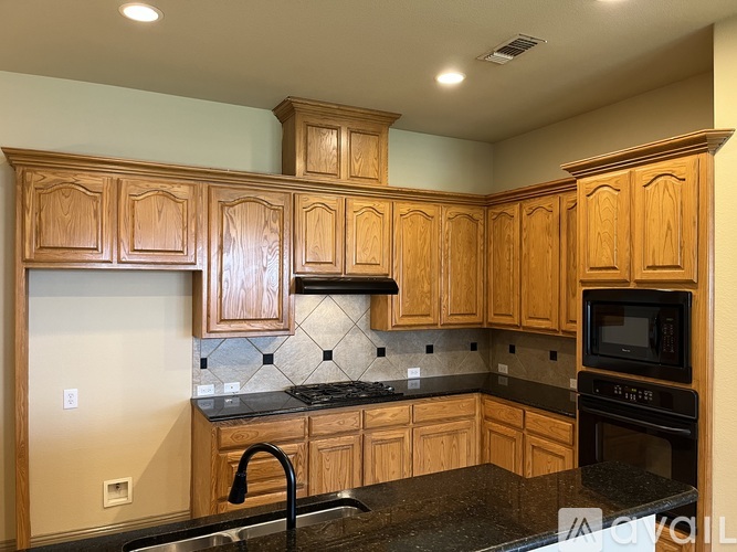 A kitchen with wooden cabinets and black countertops.