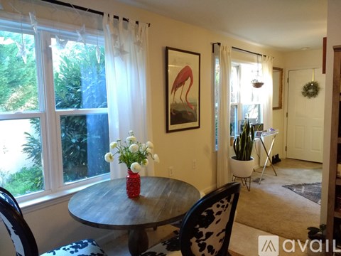 A dining room with a table, chairs, and a painting of a flamingo.