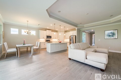 A modern living room with a dining table and a kitchen in the background.