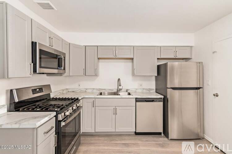 A kitchen with a stove top oven, microwave, refrigerator, and sink.