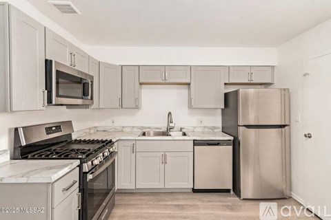 A kitchen with a stove top oven, microwave, refrigerator, and sink.