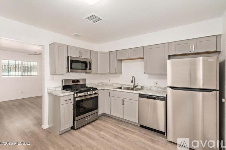 A kitchen with stainless steel appliances and wooden floors.