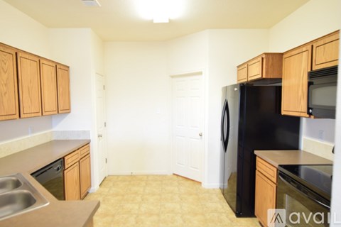 A kitchen with wooden cabinets and a black refrigerator.