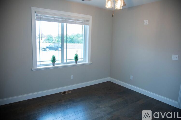 A room with a large window and a view of a parking lot and trees.