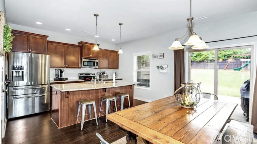 A modern kitchen with wooden table and stainless steel appliances.