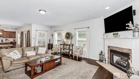 A living room with a fireplace and a television mounted above it.
