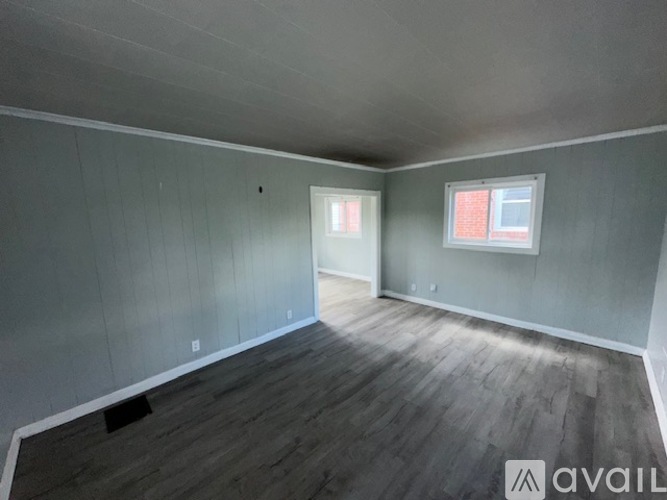A room with grey walls and wooden flooring is available for rent.