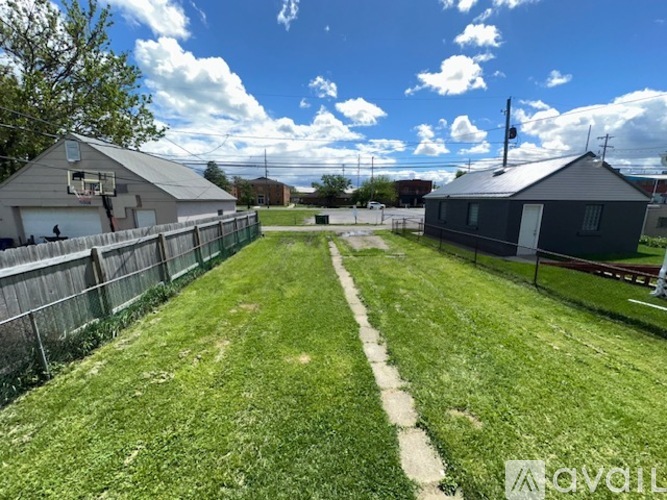 A backyard with a fence and a small building.