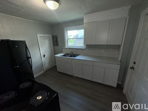 A kitchen with a black fridge and white cabinets.