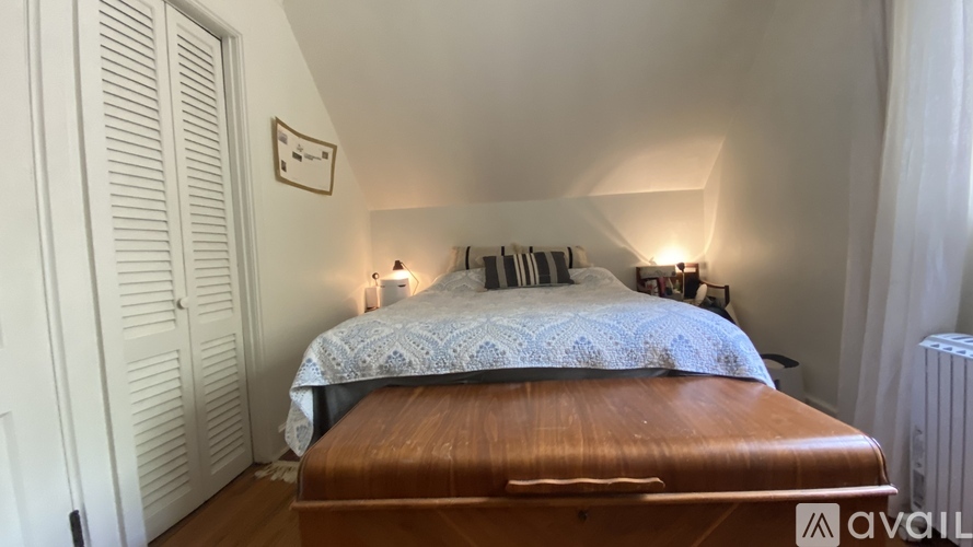 A bedroom with a bed, a wall-mounted shelf, and a radiator.