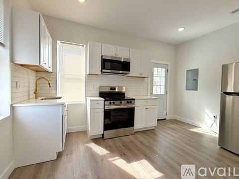 A kitchen with white cabinets and a wooden floor.