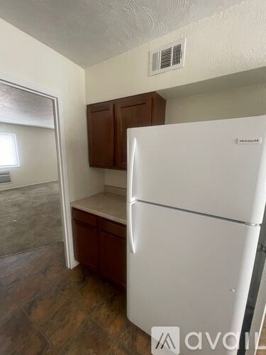 A white refrigerator is in a kitchen with wood cabinets.