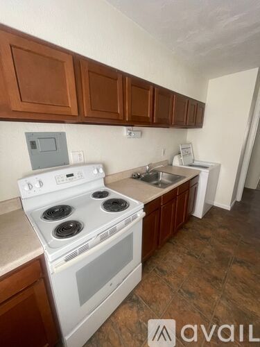 A kitchen with a white stove top oven and brown cabinets.