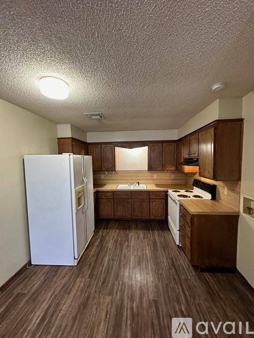 A kitchen with a white refrigerator, wooden cabinets, and a white stove top oven.