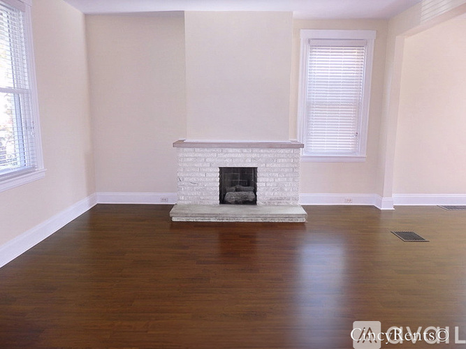 A white fireplace in a room with wooden floors.