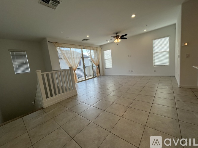 A spacious living room with a tiled floor and a ceiling fan.