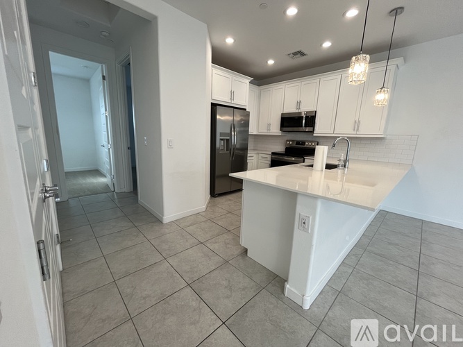 A kitchen with a black refrigerator, white countertops, and a tiled floor.
