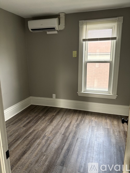 A room with a window and a wall-mounted air conditioner.