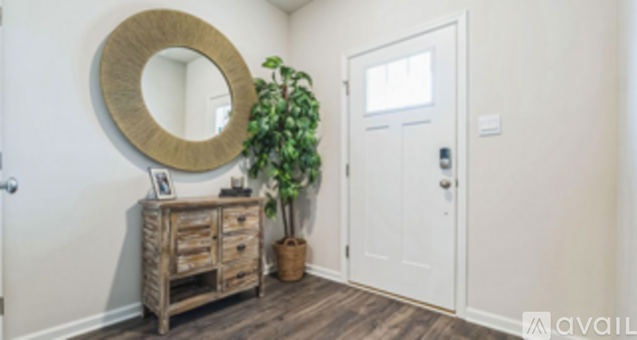 A white door is in a room with a wooden dresser and a mirror.