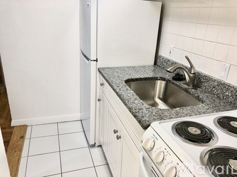 A kitchen with a white stove, sink, and refrigerator.