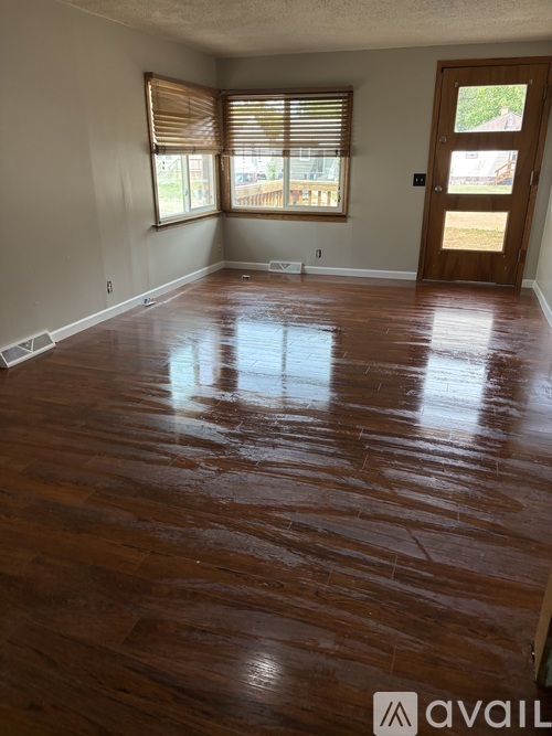 A room with wooden flooring and a door leading outside.