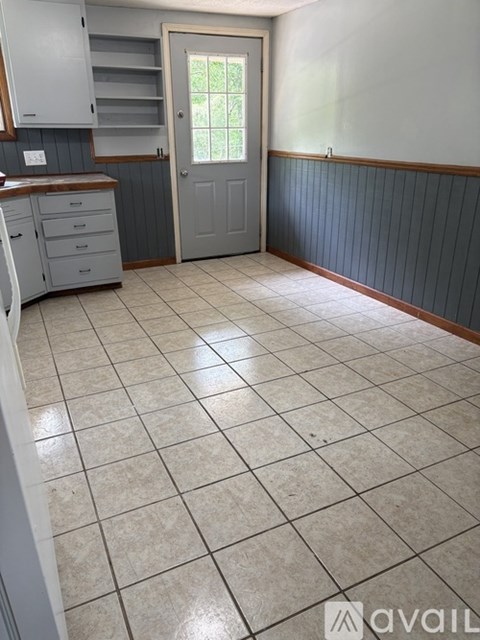 A kitchen with a tile floor and a door leading outside.