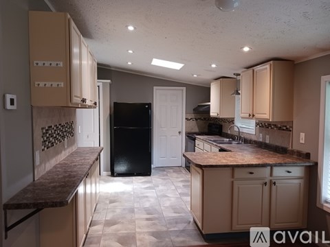 A kitchen with a black refrigerator and brown cabinets.