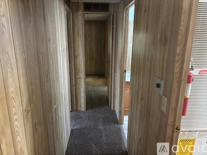 A hallway with wooden walls and a grey carpet.
