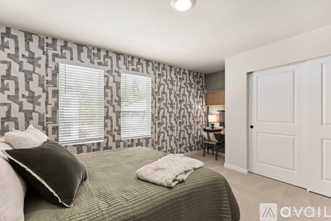 A bedroom with a patterned wallpaper and a bed with a green blanket.