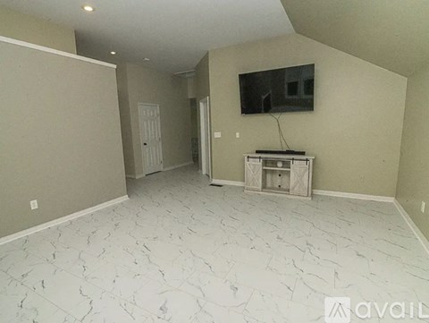A spacious living room with a television and a white marble floor.